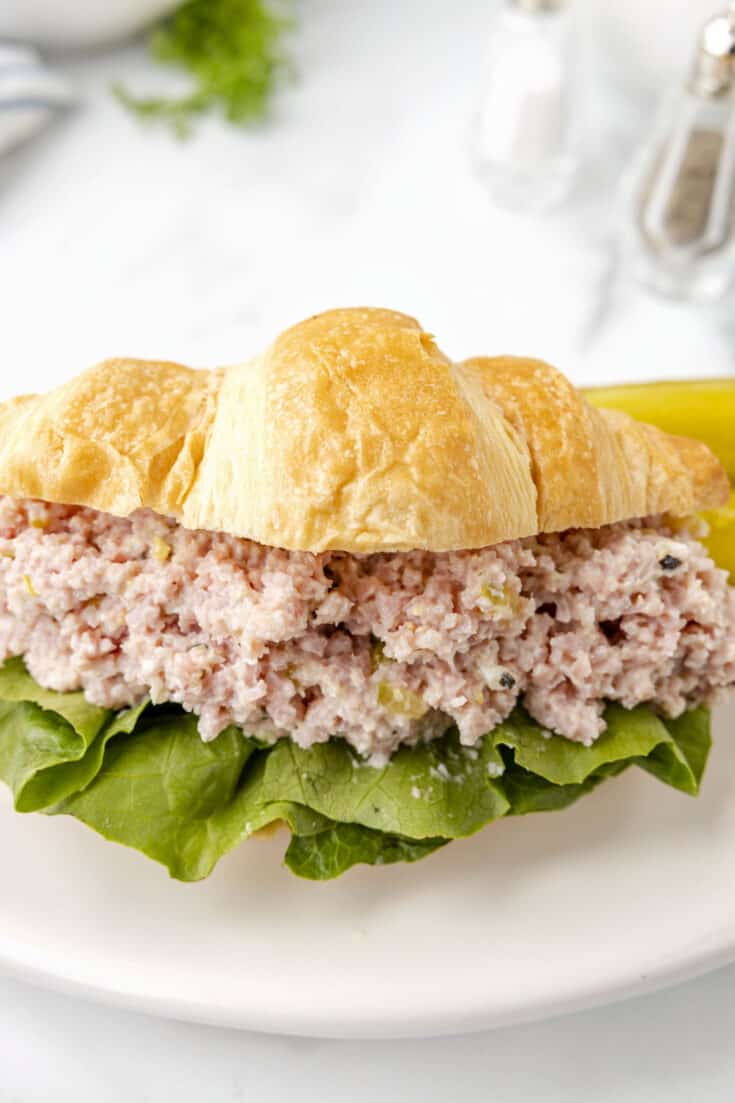Ham salad on a croissant with lettuce.